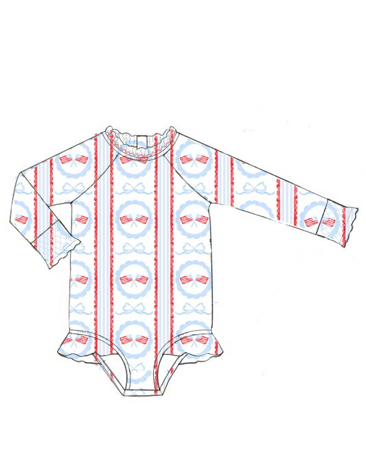 Girls long sleeve All American rash guard swimsuit with smocked bow detail, scalloped American flag print, ruffles, and snaps for sizes 3M–3T.