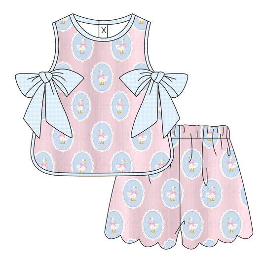Children's pink dress with blue patterns and bows on a white background