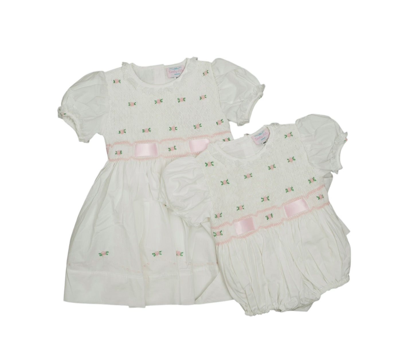 White baby dress and bloomers with pink accents on a white background
