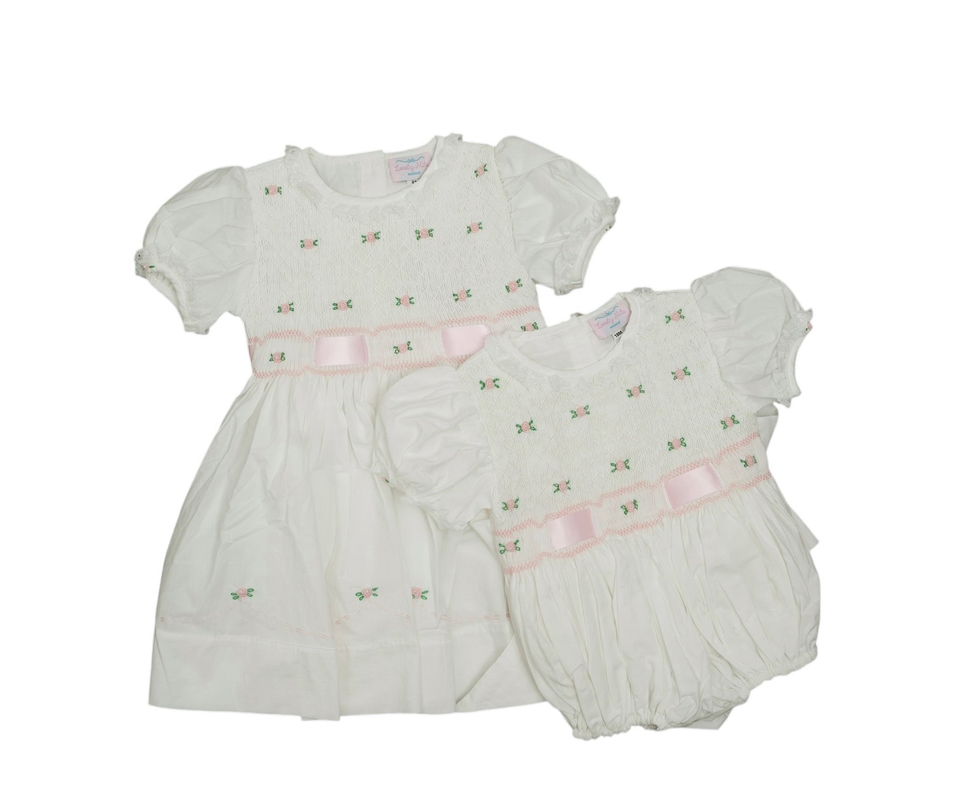 White baby dress and bloomers with pink accents on a white background