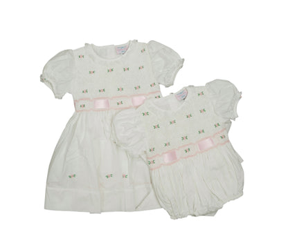White baby dress and bloomers with pink accents on a white background