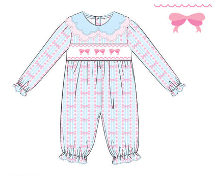 A flat line-art illustration of a long-sleeve footed baby romper with a light blue and pink patterned body, a light blue collar, and pink bows across the chest. The image is on a white background with a small pink bow graphic in the top right and text in the bottom left reading 'custom knit 2026 0702XK'.