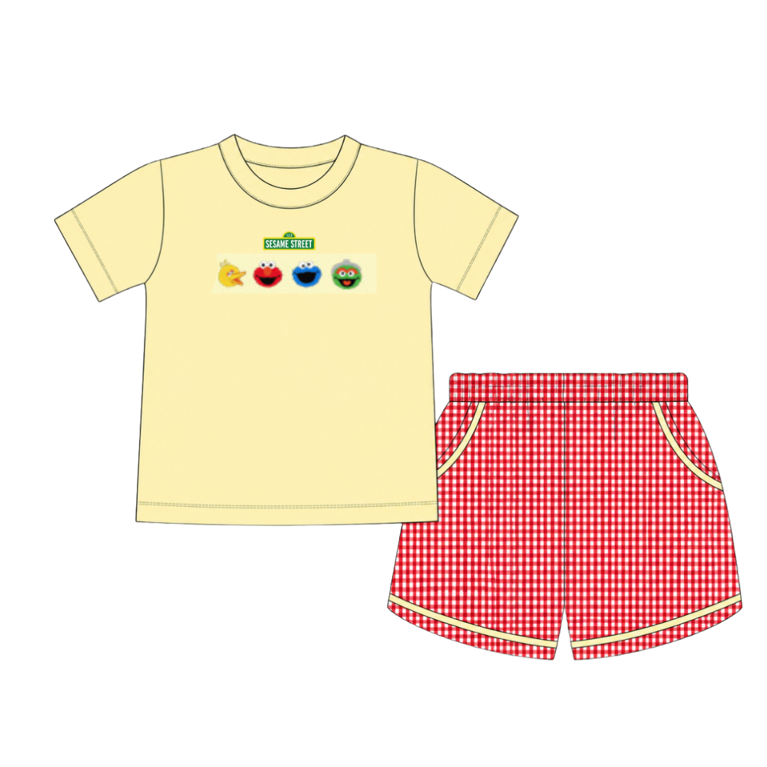 A children's two-piece outfit set featuring a pale yellow short-sleeve t-shirt with Sesame Street character graphics and red-and-white gingham shorts with yellow trim.