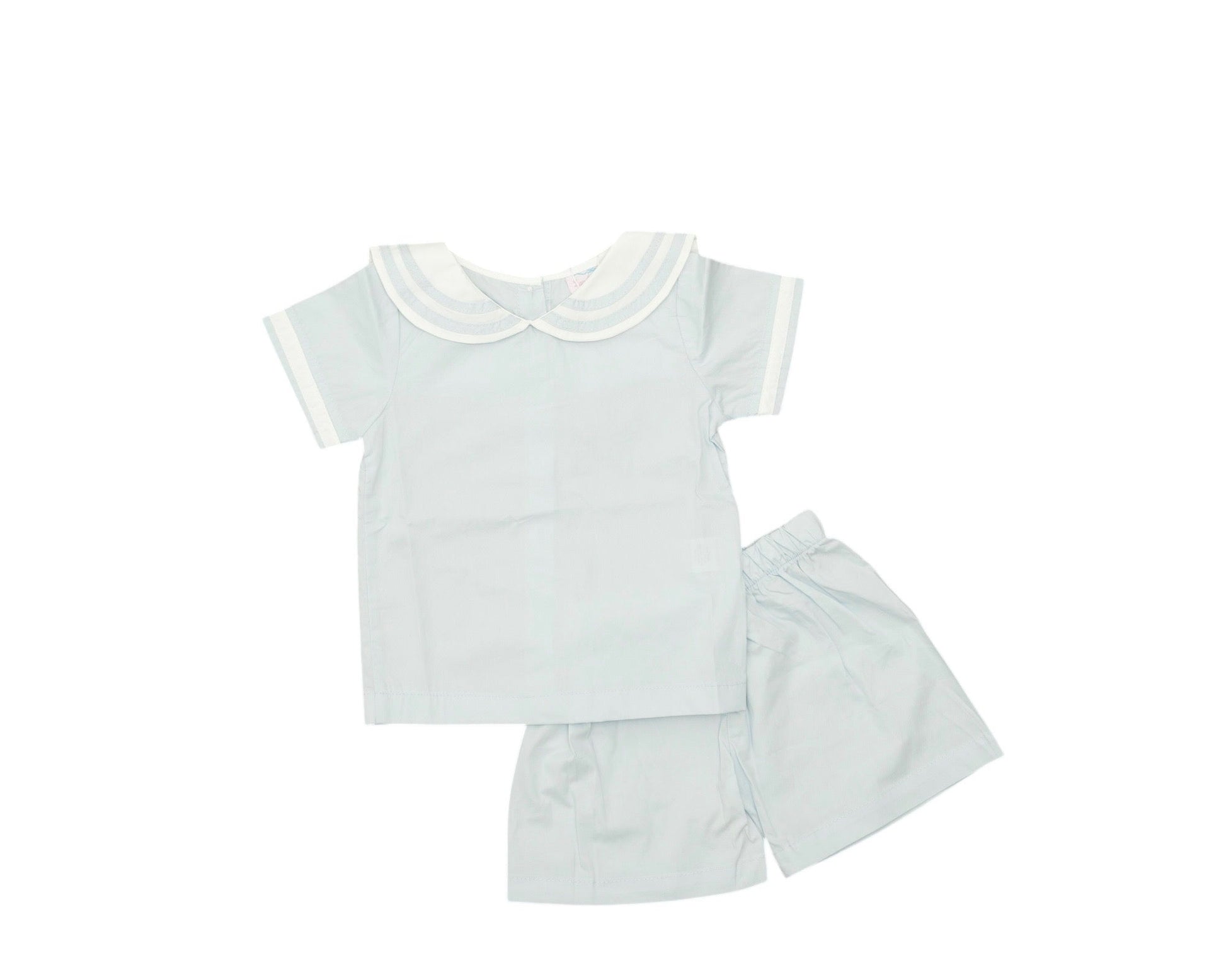 White baby outfit with shirt, shorts, and skirt on a white background