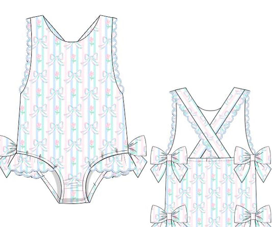 Floral bow Tropical Girl Swimsuit made with rashguard swim material. Features bows on the back and snaps for sizes NB–3T. Perfect for beach and pool.