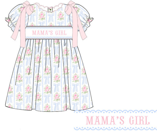 Blushing Bows hand-smocked dress in 100% cotton with bows and roses print, scalloped collar, Mama’s Girl embroidery, and pink satin shoulder bows.